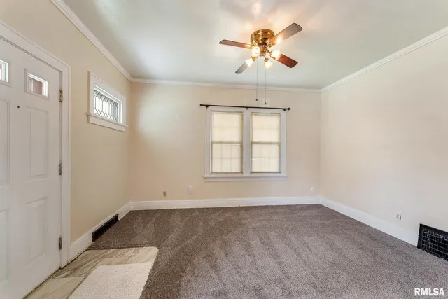 an empty room with chandelier fan and windows