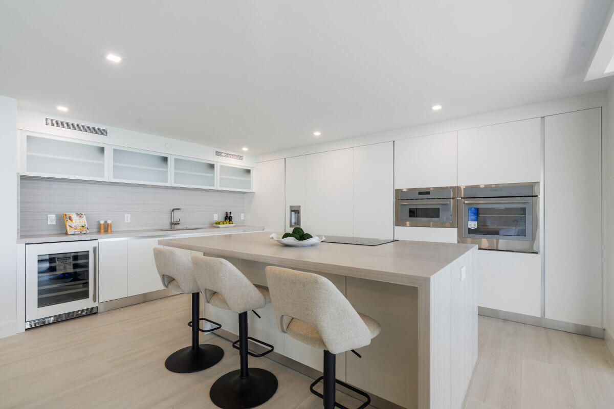 250 South Ocean Boulevard, Unit 11F Boca Raton, FL 33432 - Photo 6 of 45 a kitchen with stainless steel appliances a sink a stove a refrigerator cabinets and chairs