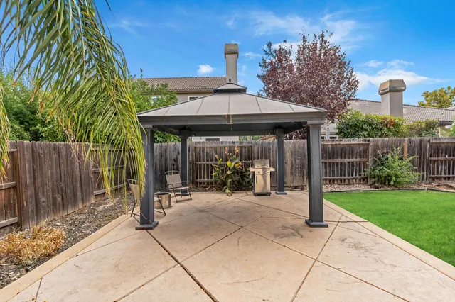 a view of a patio with a table and chairs under an umbrella with wooden fence