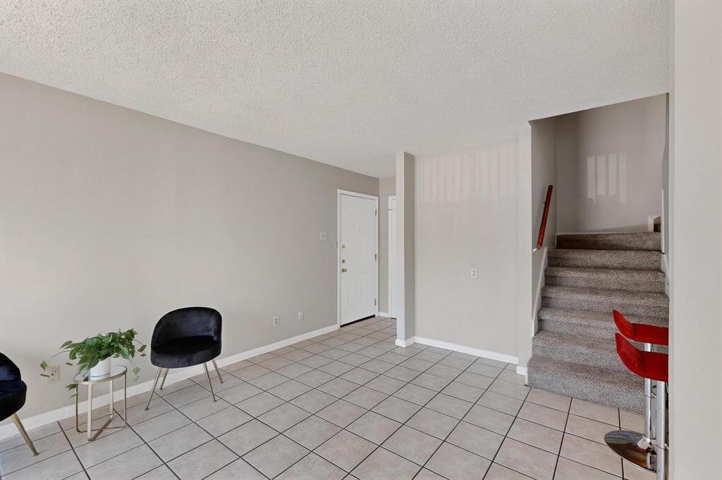 11311 Audelia Road, Unit 165 Dallas, TX 75243 - Photo 11 of 31 Living area featuring a textured ceiling, stairway, and light tile patterned flooring