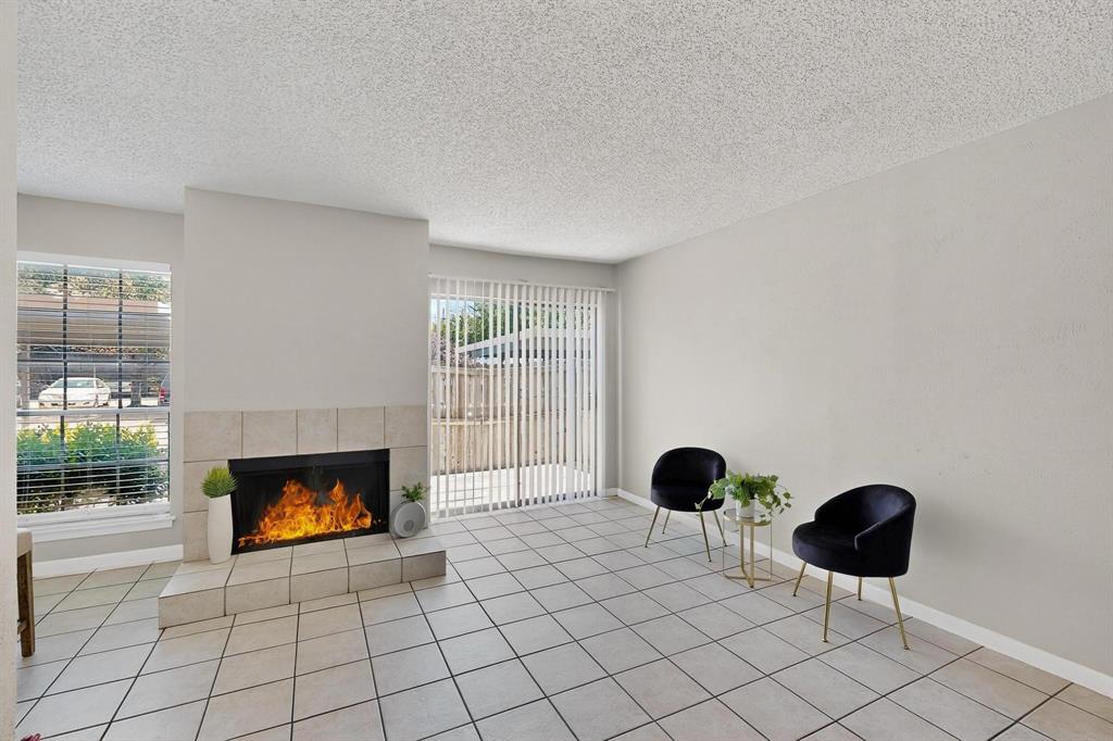 11311 Audelia Road, Unit 165 Dallas, TX 75243 - Photo 17 of 31 Unfurnished room with a tiled fireplace, a textured ceiling, light tile patterned flooring, and plenty of natural light