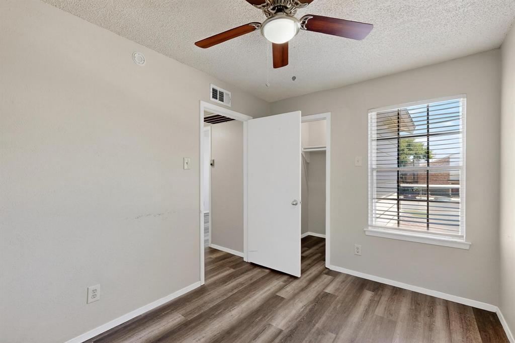 11311 Audelia Road, Unit 165 Dallas, TX 75243 - Photo 24 of 31 Unfurnished bedroom with a textured ceiling, a spacious closet, wood finished floors, and a ceiling fan