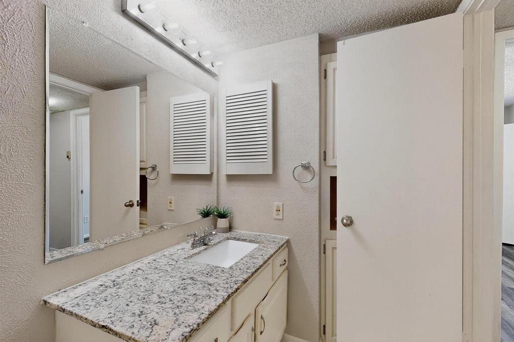 11311 Audelia Road, Unit 165 Dallas, TX 75243 - Photo 26 of 31 Bathroom featuring a textured ceiling, vanity, and a textured wall