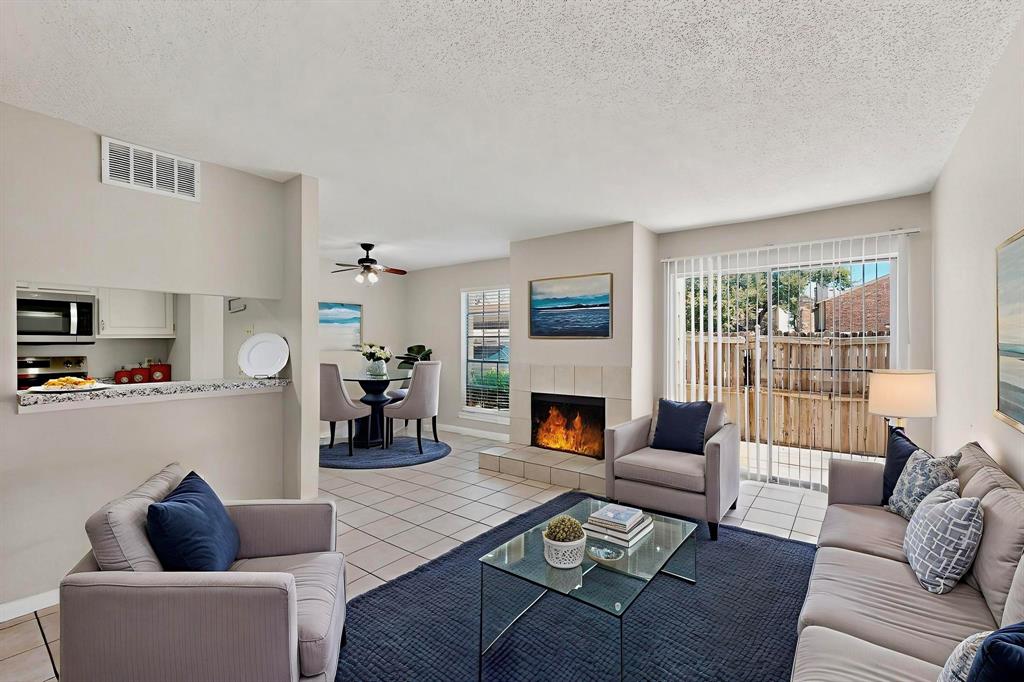 11311 Audelia Road, Unit 165 Dallas, TX 75243 - Photo 10 of 31 Living room with light tile patterned flooring, a textured ceiling, a ceiling fan, and a tile fireplace
