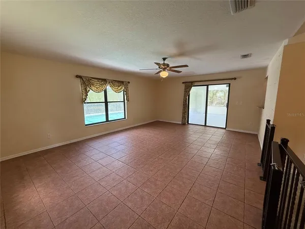 an empty room with windows and chandelier fan