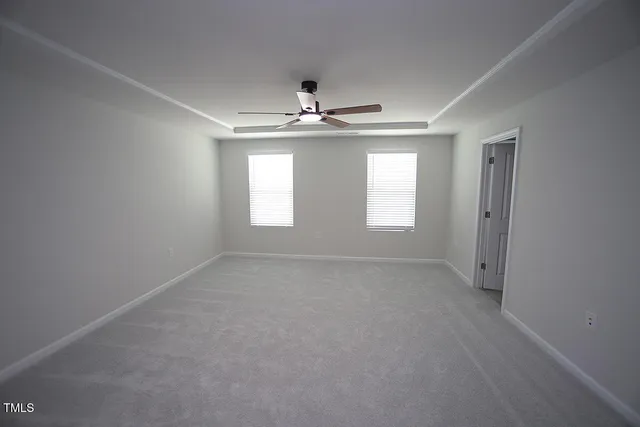 an empty room with windows and ceiling fan