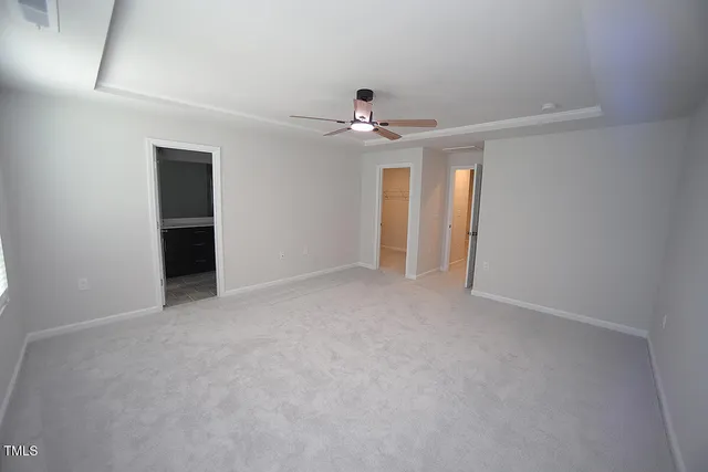 an empty room with chandelier fan and windows