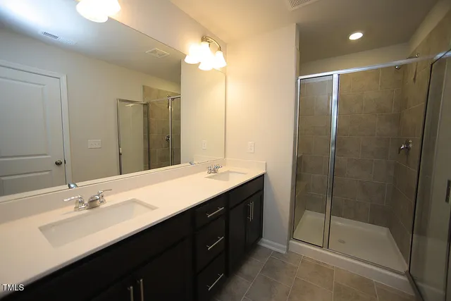 a bathroom with a double vanity sink mirror and shower