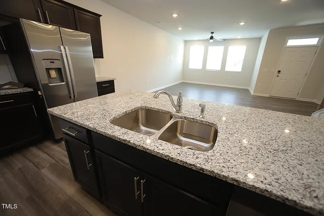 a kitchen with stainless steel appliances granite countertop a sink a refrigerator and a granite counter tops
