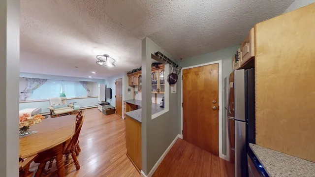 a view of a hallway with wooden floor and a kitchen