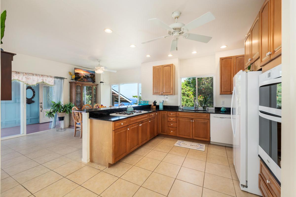 87-404 Kaohe Road Captain Cook, HI 96704 - Photo 13 of 25 a kitchen with stainless steel appliances granite countertop a refrigerator a sink and a stove