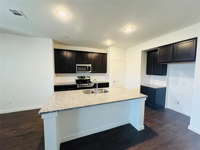 a view of kitchen with microwave stove refrigerator and wooden cabinets