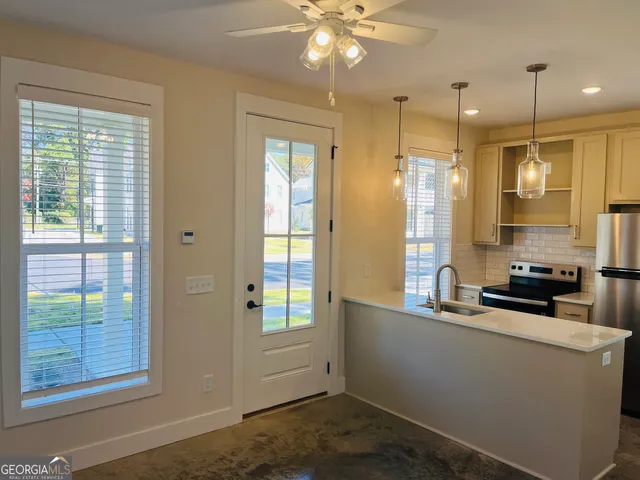 a kitchen with stainless steel appliances kitchen island granite countertop a sink a stove and a window