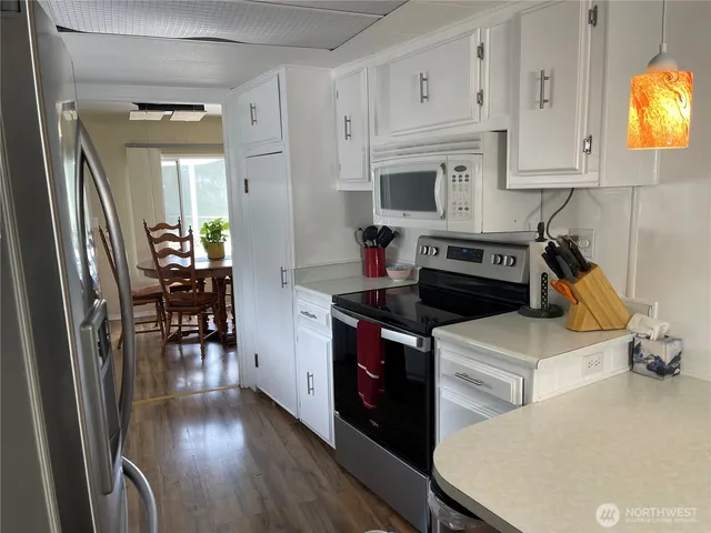 a kitchen with stainless steel appliances a stove a refrigerator a dining table and chairs