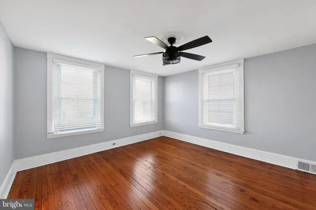 a view of empty room with wooden floor and fan