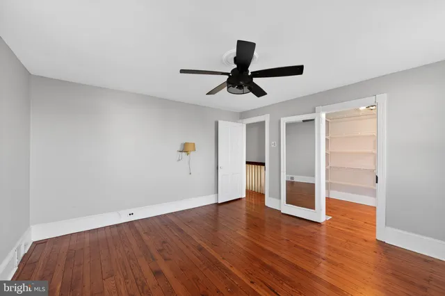 a view of empty room with wooden floor and ceiling fan