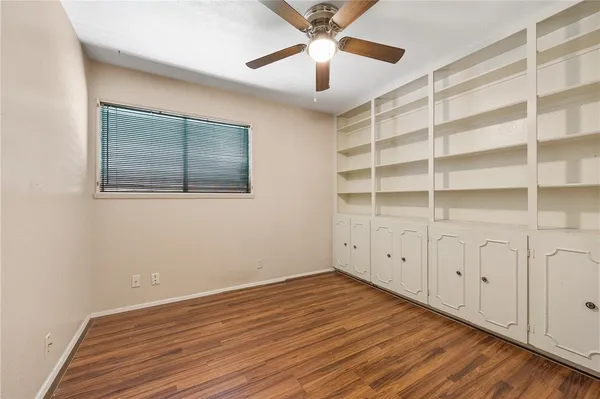 a view of an empty room with wooden floor and closet