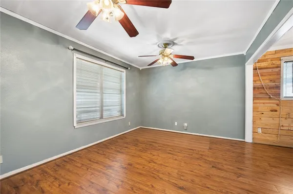 a view of empty room with wooden floor and fan