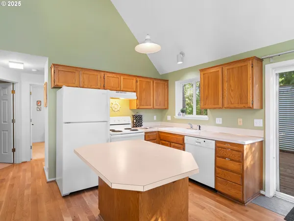 a kitchen with stainless steel appliances a refrigerator a sink dishwasher a stove top oven a dining table and chairs with wooden floor