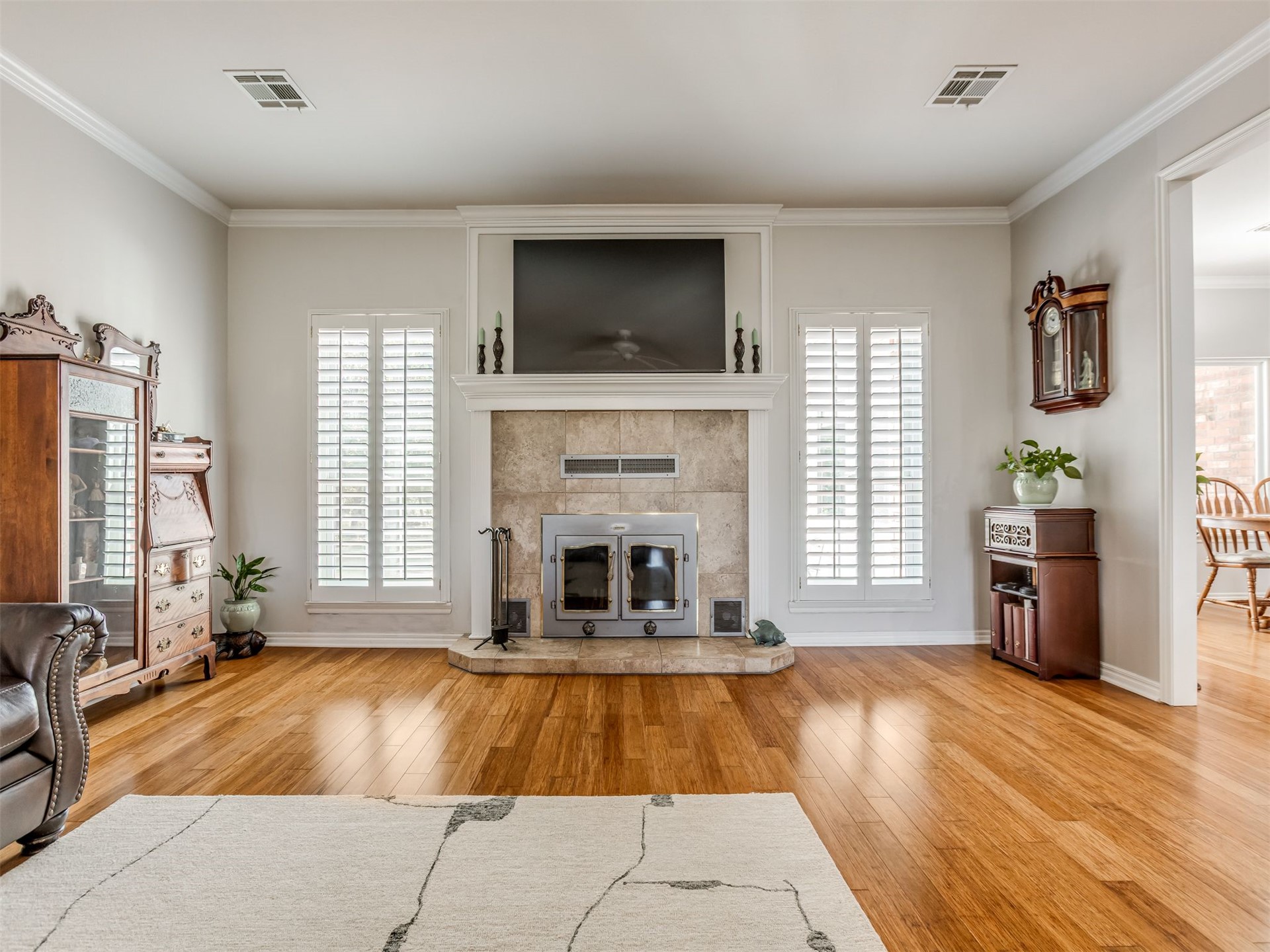 119 Mainsail Road Stigler, OK 74462 - Photo 9 of 52 Wood-finish flooring, crown molding, stone-clad fireplace with mantel, and white plantation shutters