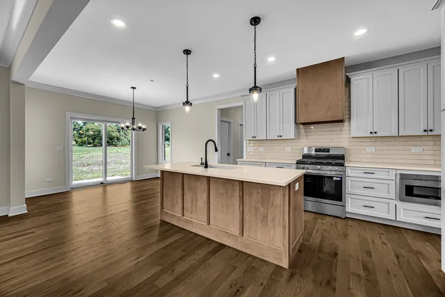 a kitchen with stainless steel appliances granite countertop a stove a sink and white cabinets with wooden floor
