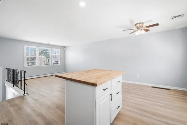 a hall with kitchen island white cabinets and wooden floor