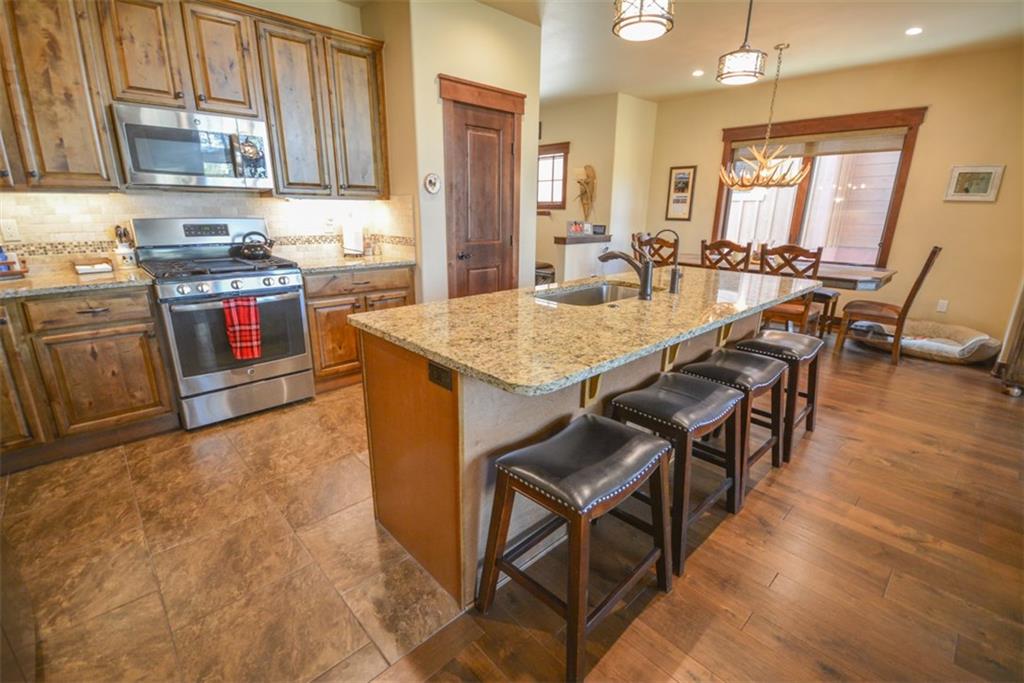 833 Independence Road, Unit 6A Keystone, CO 80435 - Photo 3 of 35 a kitchen with stainless steel appliances granite countertop a stove a sink a dining table and chairs with wooden floor