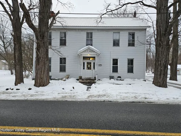 a front view of a house with snow on side of road