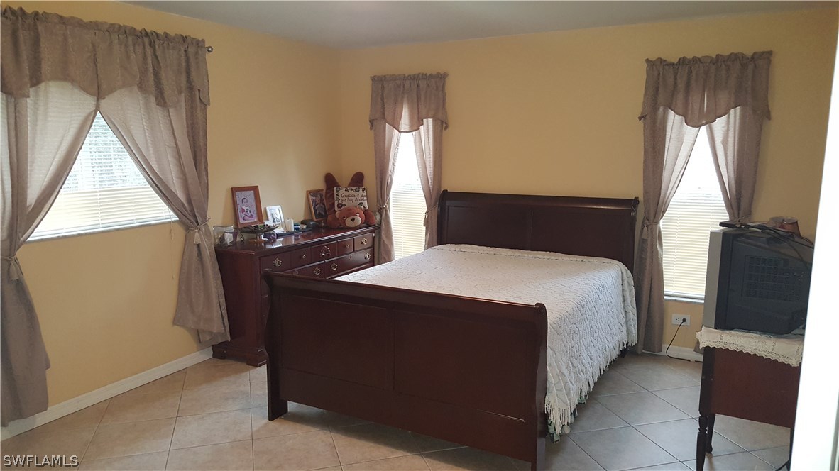 9041 Buckingham Road Fort Myers, FL 33905 - Photo 7 of 11 a bedroom with a bed and a flat tv screen next to a window
