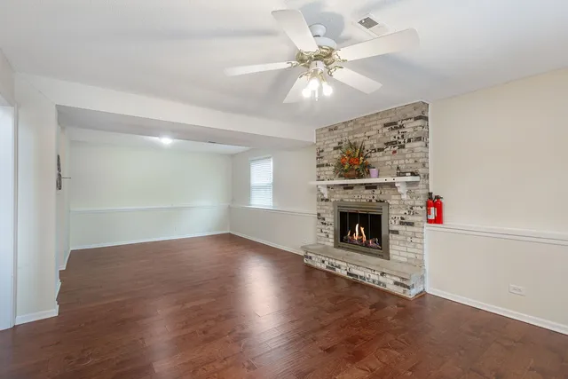an empty room with wooden floor fireplace and window