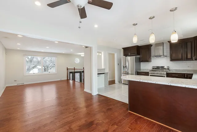 a large kitchen with stainless steel appliances kitchen island a large counter top and a refrigerator