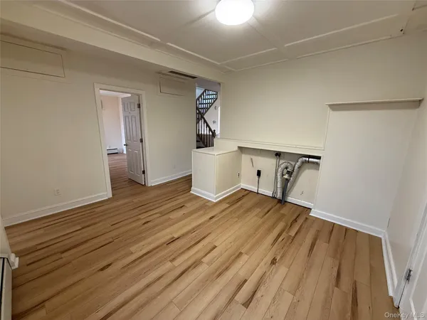 a view of a bedroom with wooden floor and white walls