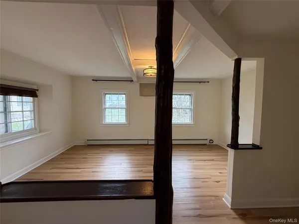 a view of an empty room with window and wooden floor