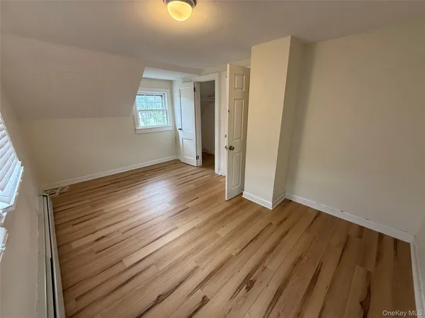 a view of an empty room with window and wooden floor