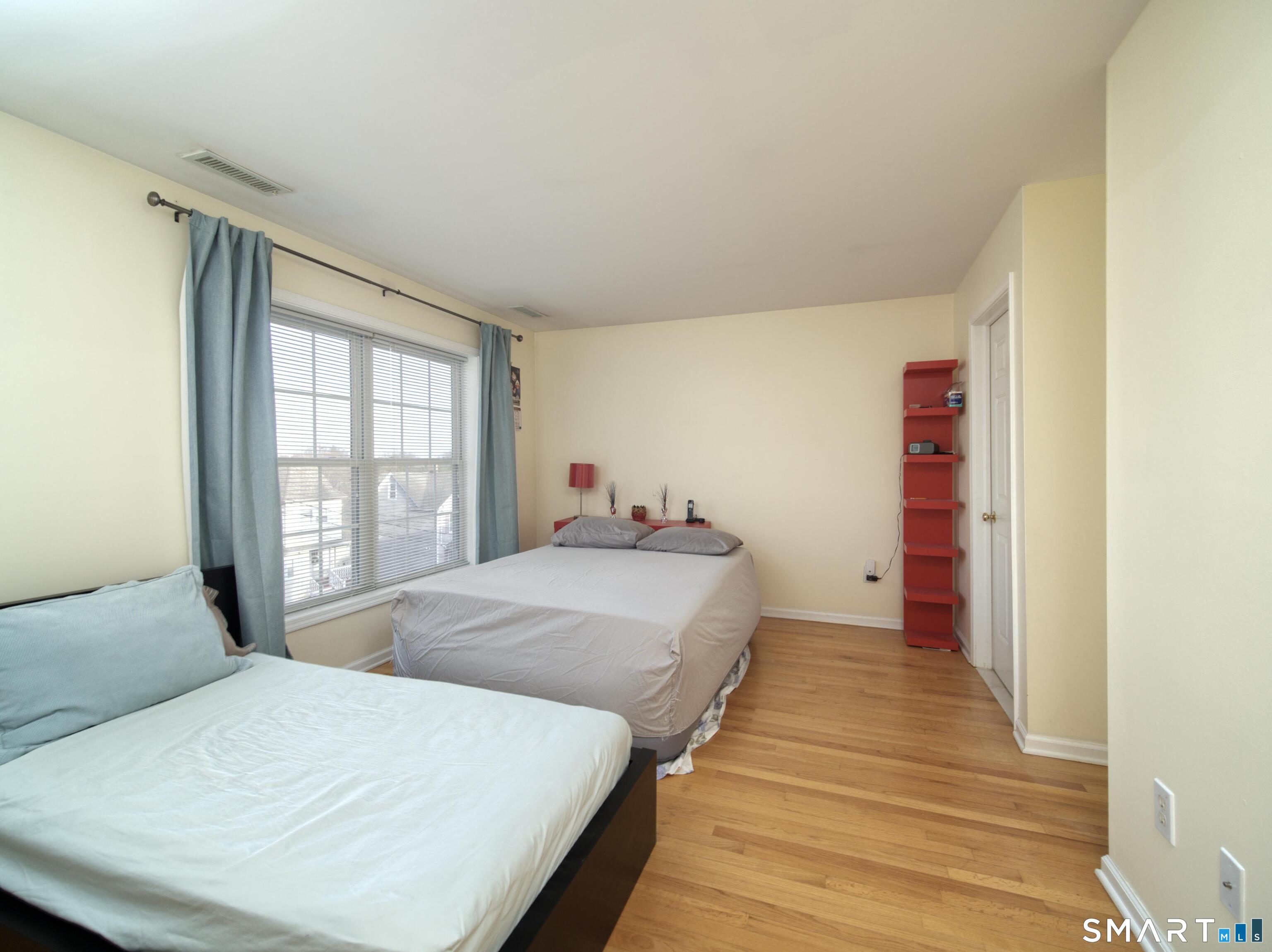 65 Benton Street, Unit 65 Fairfield, CT 06825 - Photo 18 of 35 a bedroom with a bed and wooden floor