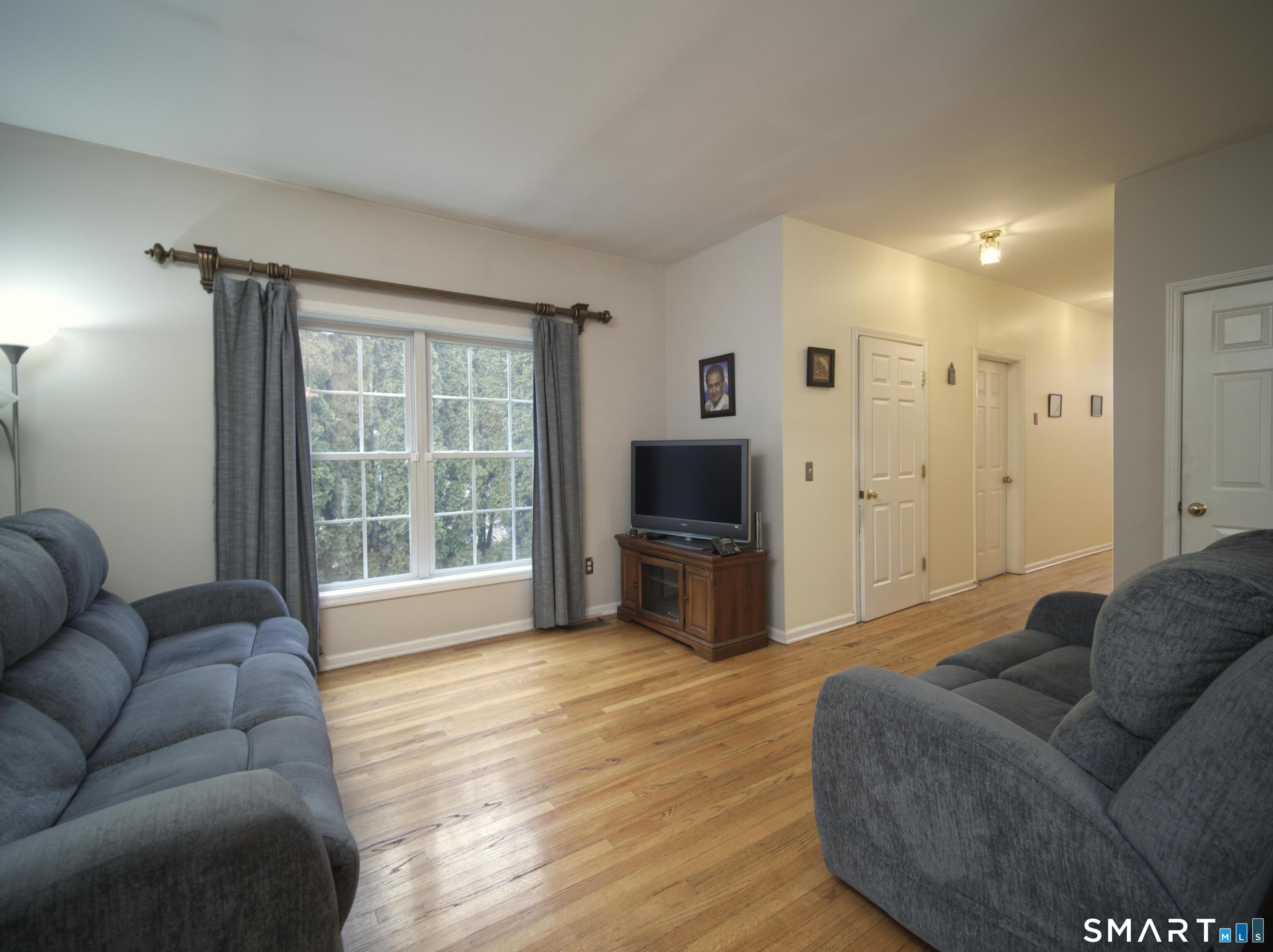 65 Benton Street, Unit 65 Fairfield, CT 06825 - Photo 6 of 35 a living room with furniture a flat screen tv and a large window