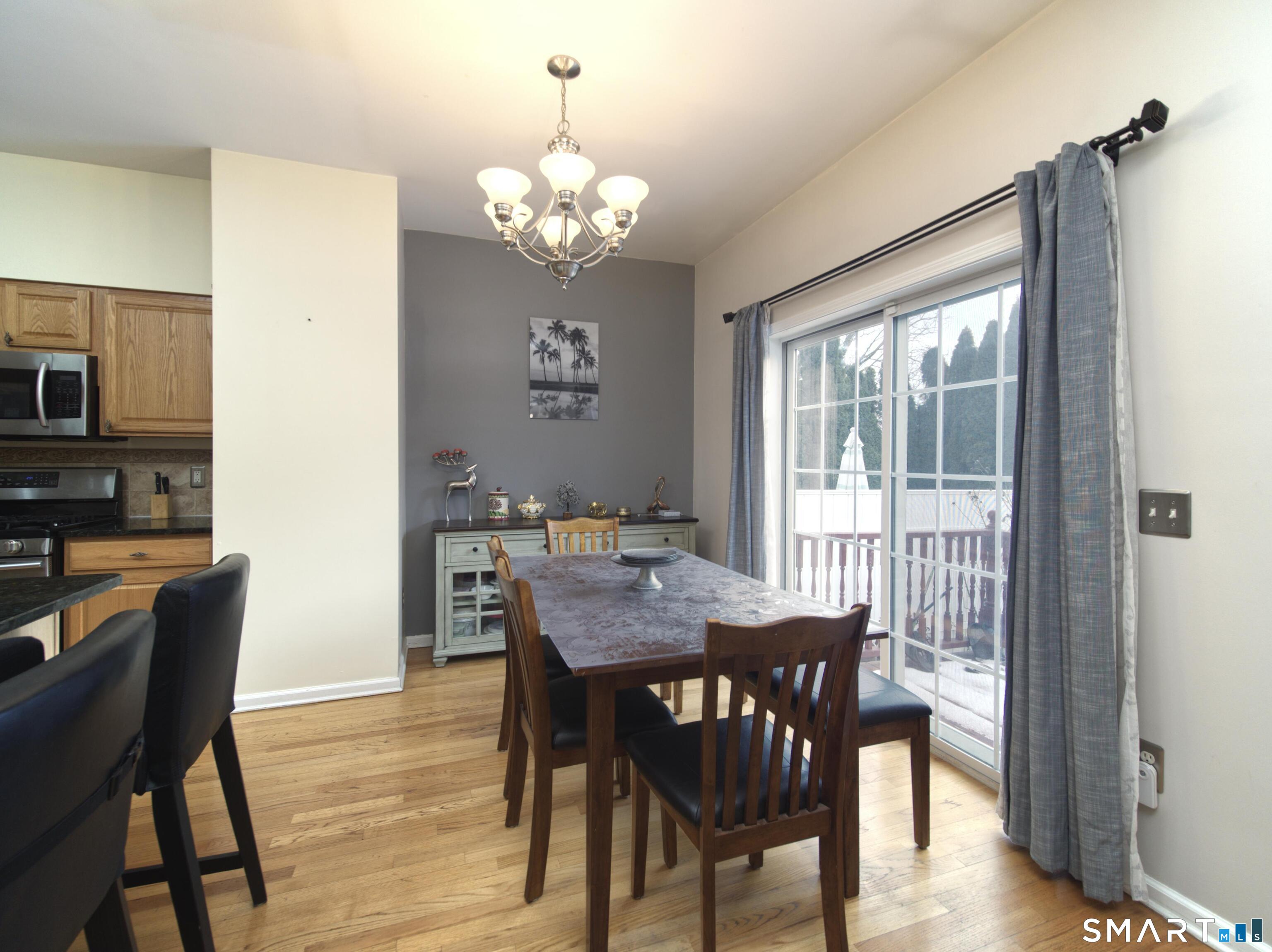 65 Benton Street, Unit 65 Fairfield, CT 06825 - Photo 7 of 35 a view of a dining room with furniture a chandelier and wooden floor