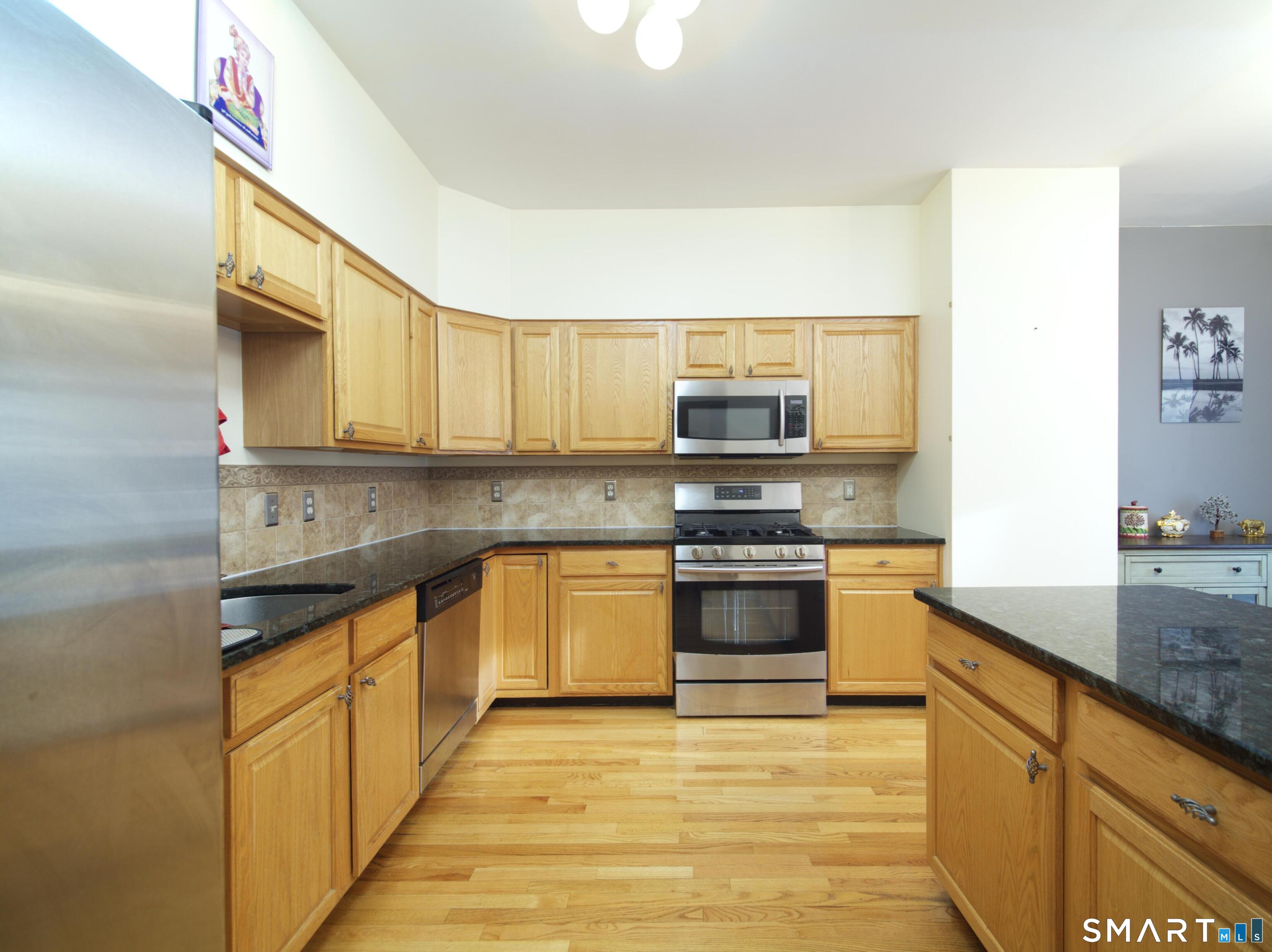 65 Benton Street, Unit 65 Fairfield, CT 06825 - Photo 9 of 35 a kitchen with stainless steel appliances granite countertop a stove a sink and a microwave