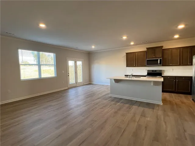 a large kitchen with stainless steel appliances a large counter top a stove a sink dishwasher and a microwave oven on the wooden floor