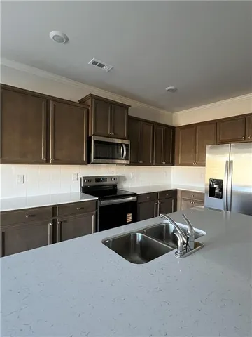 a kitchen with stainless steel appliances a sink a stove a microwave a sink a refrigerator and cabinets