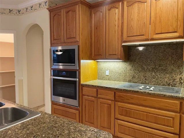 a kitchen with granite countertop a refrigerator and cabinets