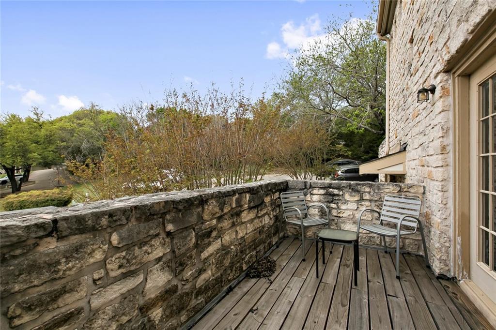 9201 Simmons Road, Unit 117 Austin, TX 78759 - Photo 10 of 11 Private outdoor balcony featuring a wood-finish deck and a stone half-wall