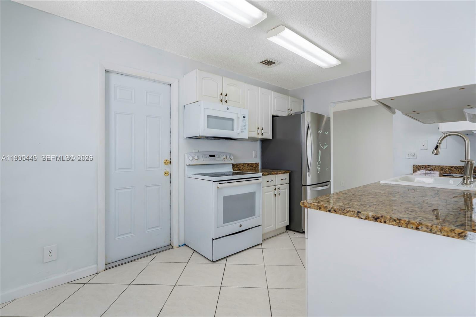 1005 Southwest 18th Street Boynton Beach, FL 33426 - Photo 14 of 44 a kitchen with granite countertop cabinets and steel stainless steel appliances