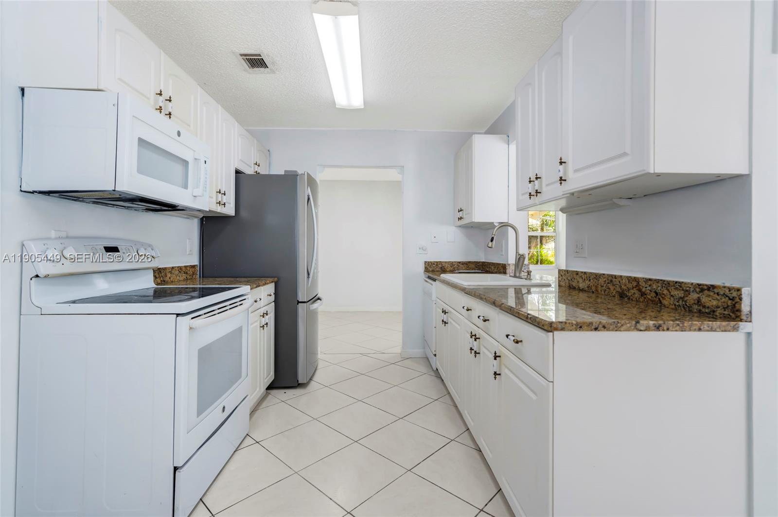 1005 Southwest 18th Street Boynton Beach, FL 33426 - Photo 15 of 44 a kitchen with granite countertop white cabinets and white appliances