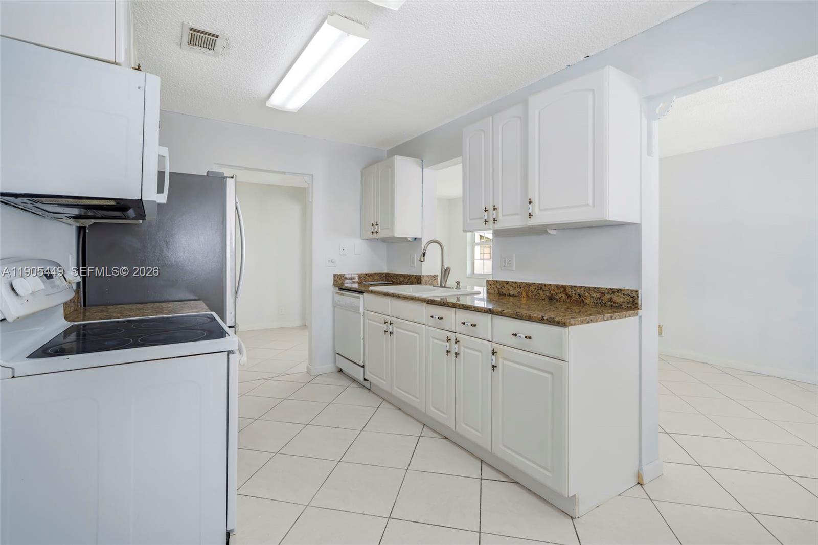 1005 Southwest 18th Street Boynton Beach, FL 33426 - Photo 16 of 44 a kitchen with granite countertop white cabinets and white appliances