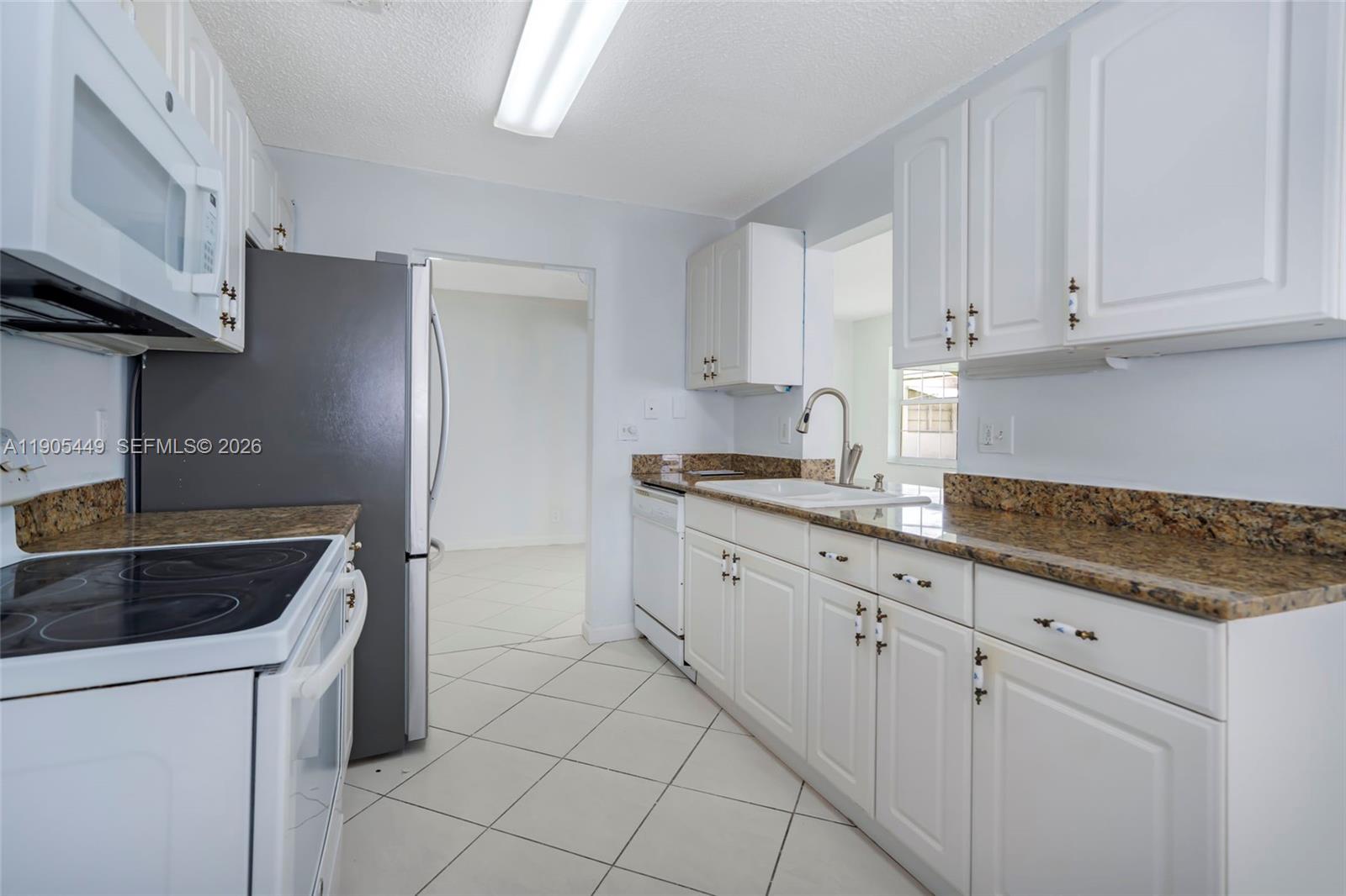 1005 Southwest 18th Street Boynton Beach, FL 33426 - Photo 17 of 44 a kitchen with granite countertop white cabinets and stainless steel appliances