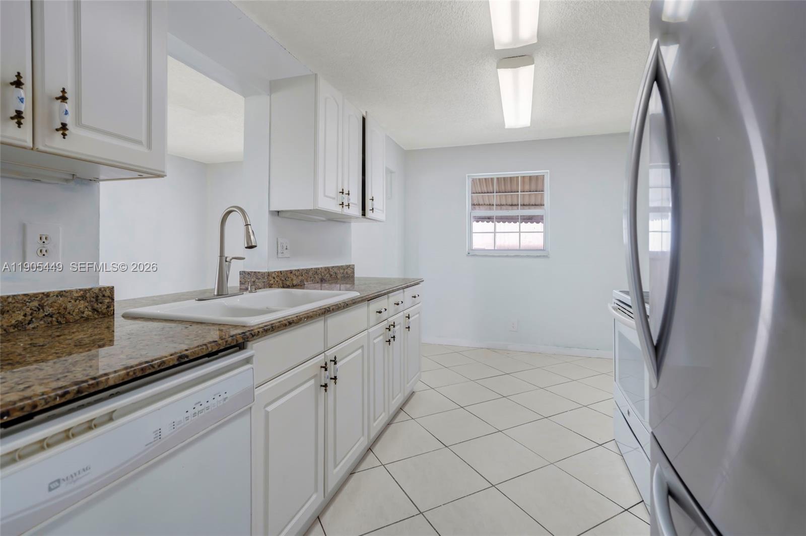 1005 Southwest 18th Street Boynton Beach, FL 33426 - Photo 18 of 44 a kitchen with granite countertop white cabinets and a sink