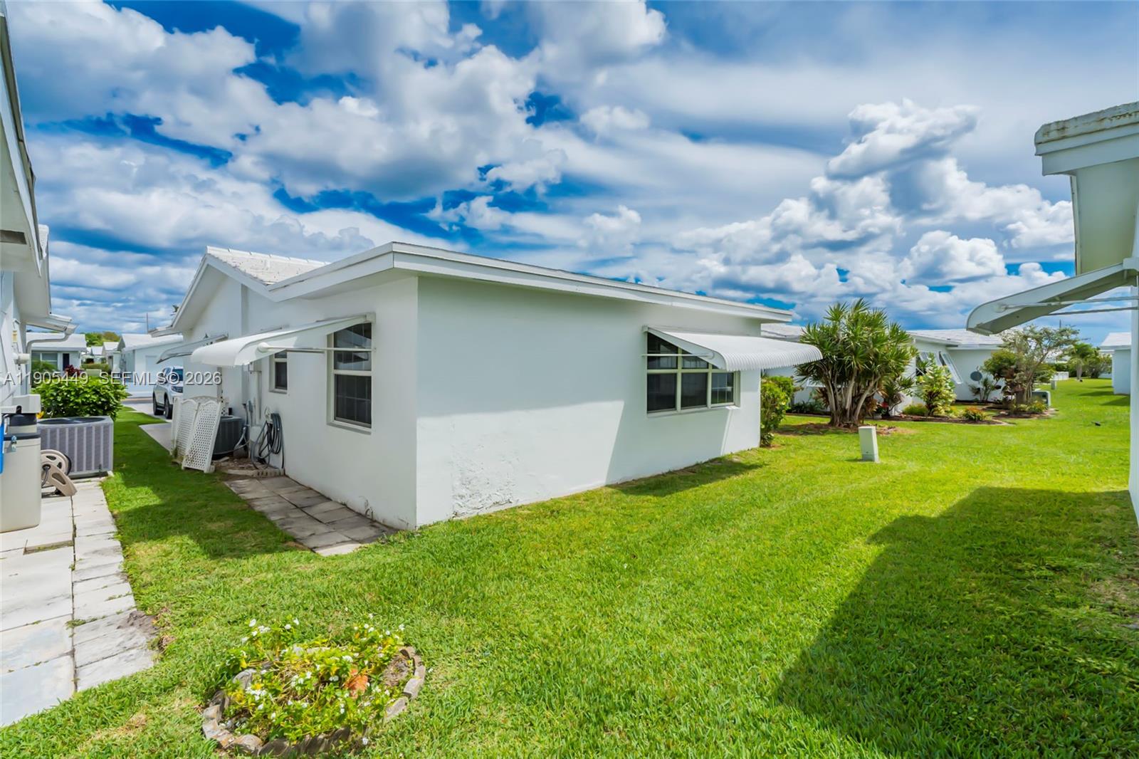 1005 Southwest 18th Street Boynton Beach, FL 33426 - Photo 30 of 44 a white house with a big yard and a large tree