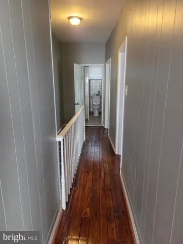 a view of a hallway with wooden floor and stairs