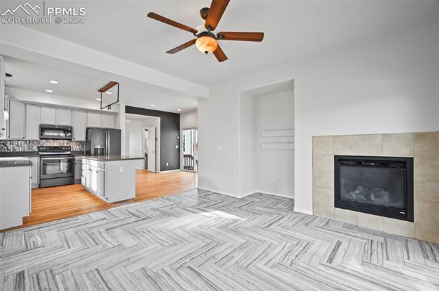 10165 Angeles Road Peyton, CO 80831 - Photo 8 of 38 Kitchen with a tiled fireplace, white cabinets, ceiling fan, stainless steel fridge with ice dispenser, and range with electric stovetop